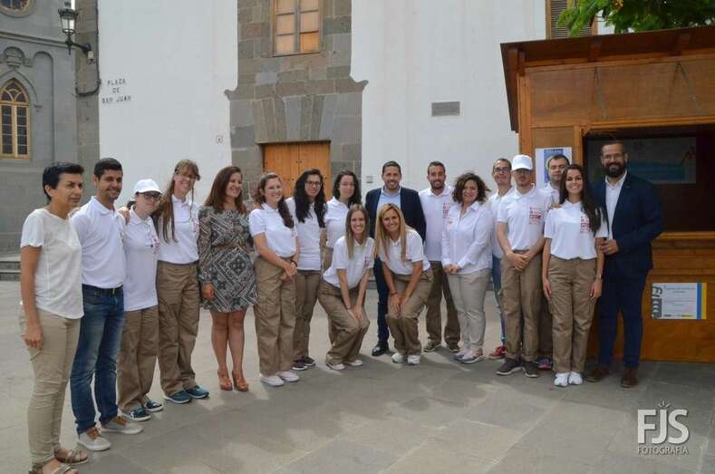 Foto de grupo de alumnos y monitores en la caseta que como punto de información turística han instalado en San Juan. Con ellos posan el alcalde y la concejala (Foto TA)